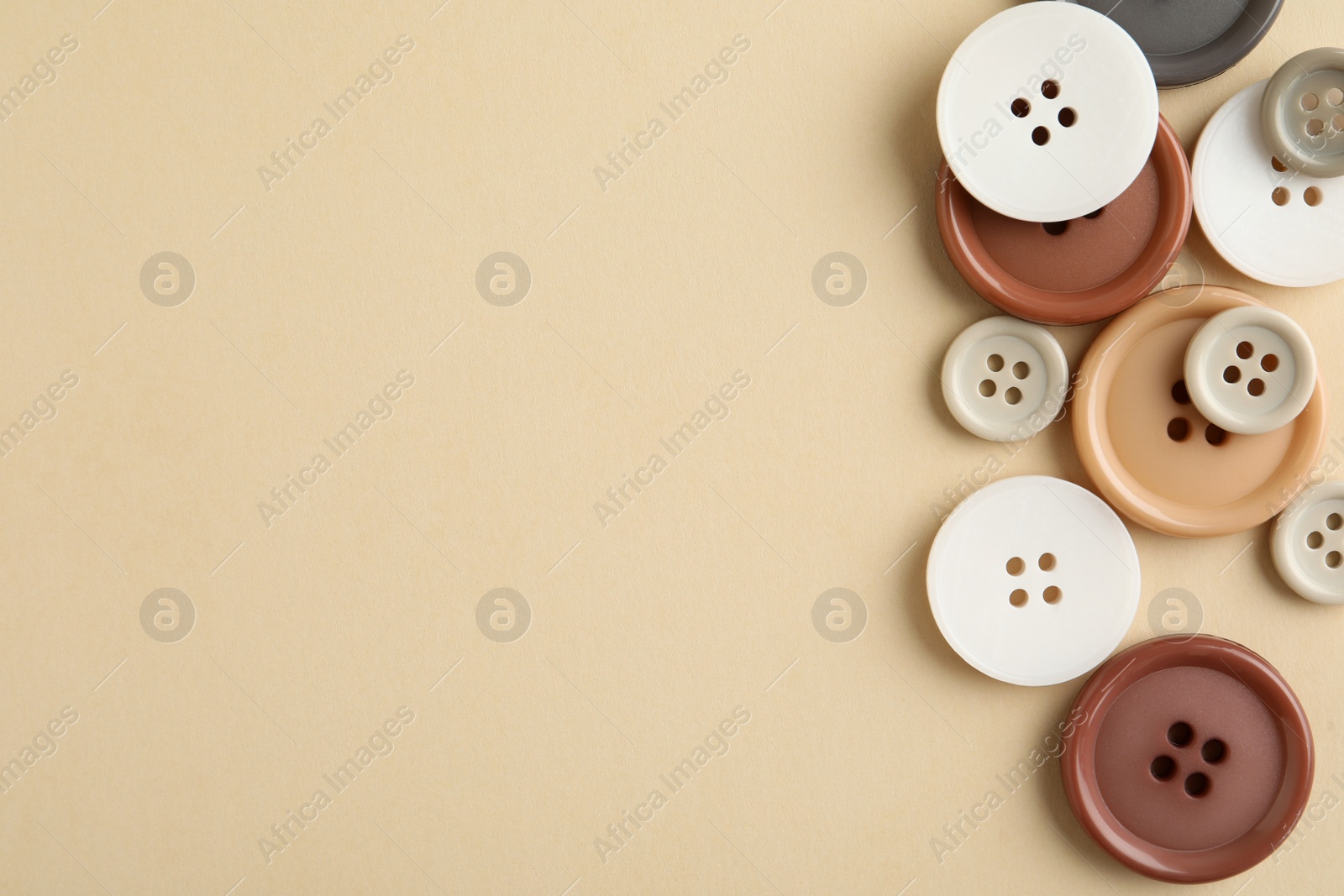 Photo of Many colorful sewing buttons on beige background, flat lay. Space for text