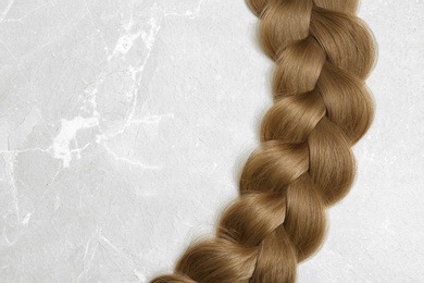 Photo of Braided hair on grey background, top view with space for text