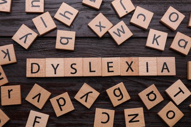 Photo of Squares with word Dyslexia on wooden background, flat lay