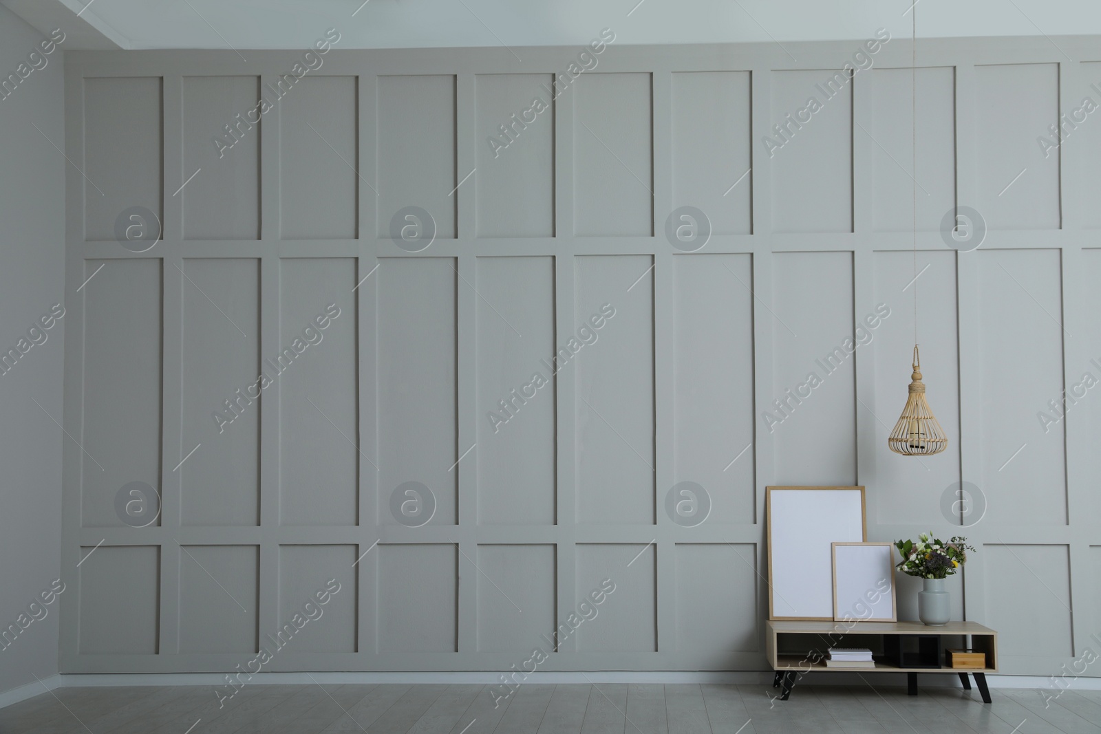 Photo of Simple room interior with console table, decor elements and empty wall. Space for design