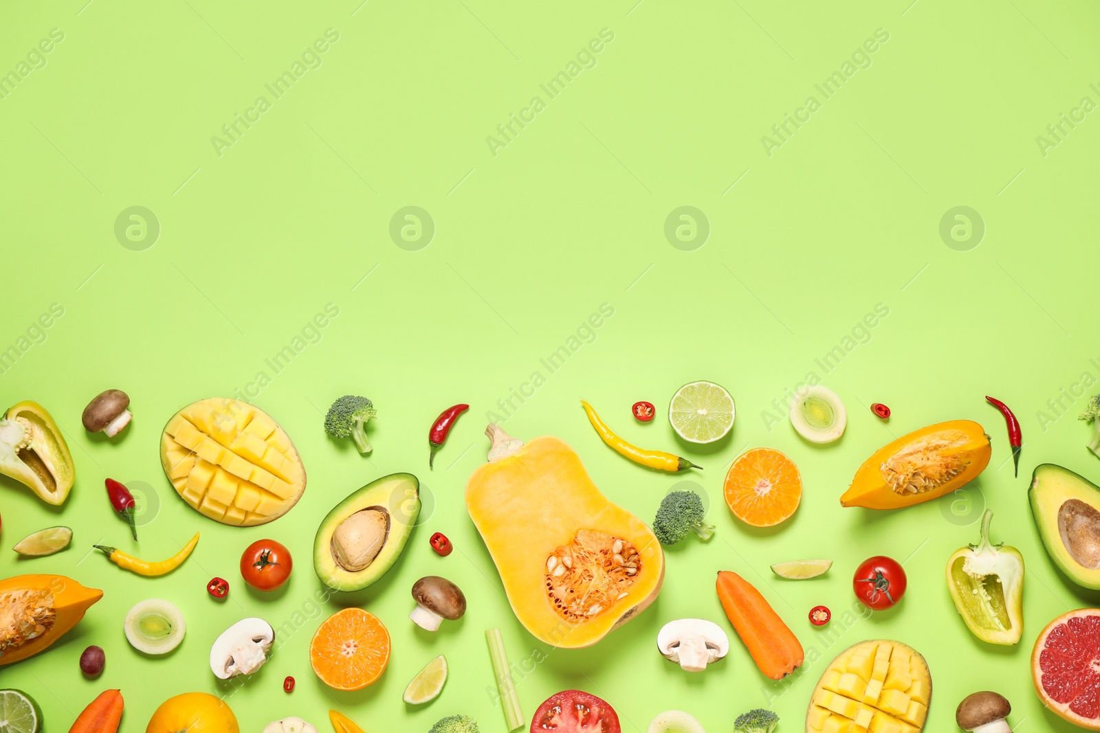 Photo of Flat lay composition with fresh organic fruits and vegetables on light green background. Space for text