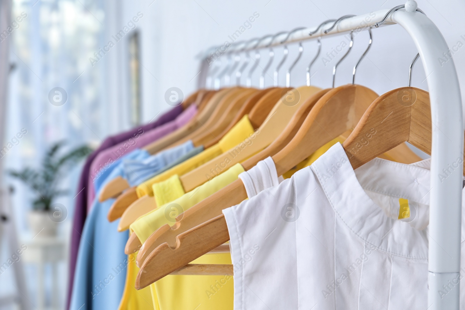 Photo of Stylish clothes hanging on wardrobe rack indoors, closeup