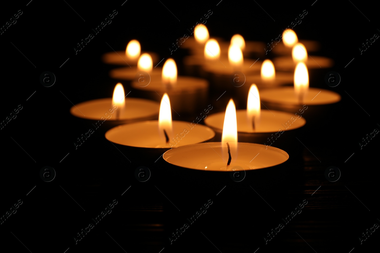 Photo of Burning candles on black background, closeup. Memory day