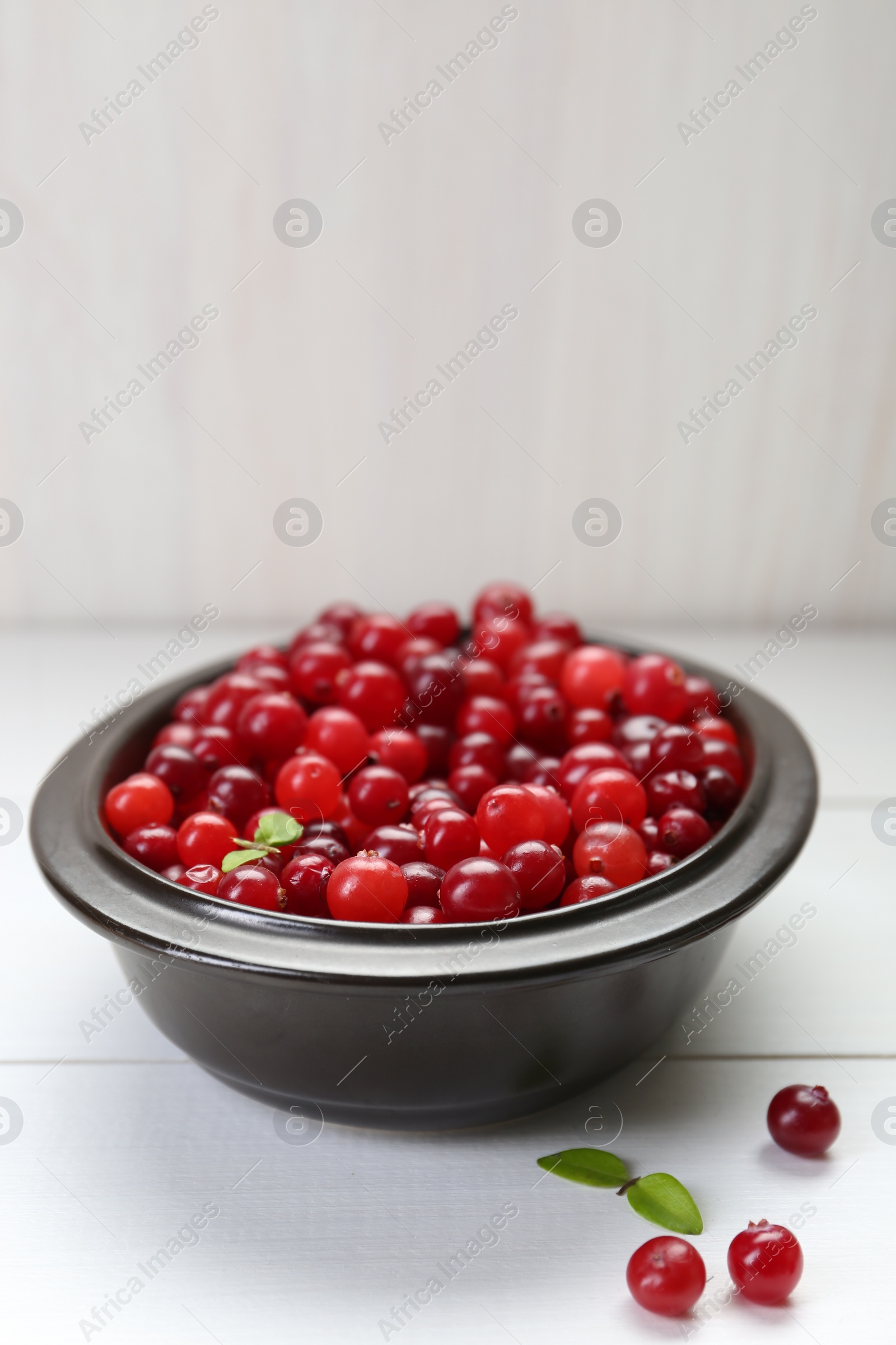 Photo of Fresh ripe cranberries on white wooden table, space for text