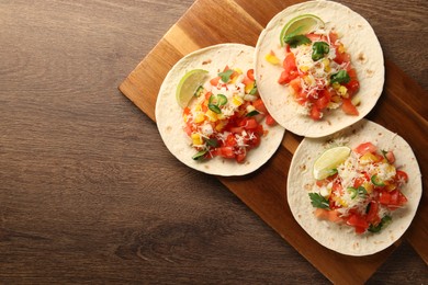 Photo of Delicious tacos with vegetables and lime on wooden table, top view. Space for text