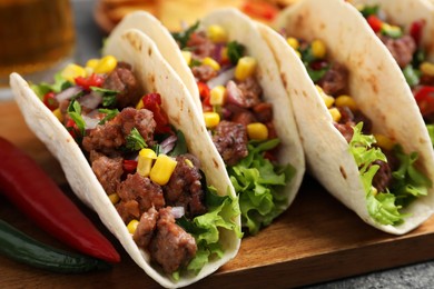 Photo of Delicious tacos with meat and vegetables on table, closeup