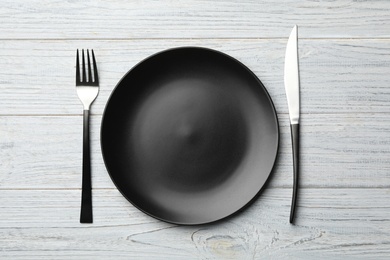 Photo of Stylish ceramic plate and cutlery on white wooden background, flat lay