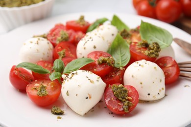 Photo of Tasty salad Caprese with tomatoes, mozzarella balls and basil on plate, closeup