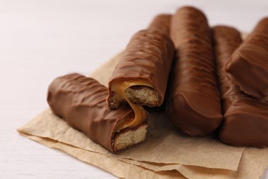 Photo of Tasty chocolate bars with caramel on white wooden table, closeup