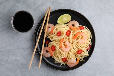 Tasty spaghetti with shrimps, chili pepper, lime and soy sauce on grey table, flat lay