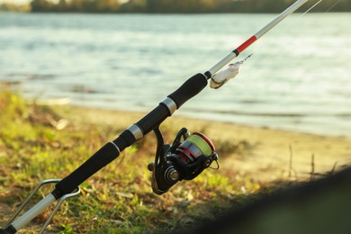 Photo of Fishing rod with reel at riverside on sunny day