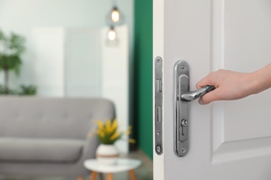 Photo of Woman opening door to stylish room, closeup. Interior design