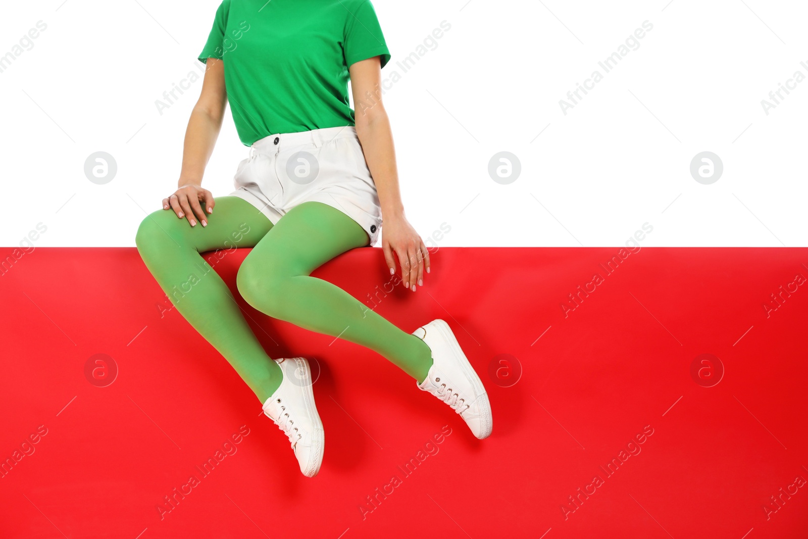 Photo of Woman wearing green tights sitting on color background, closeup