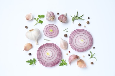 Fresh garlic, onion rings and spices on white table, flat lay