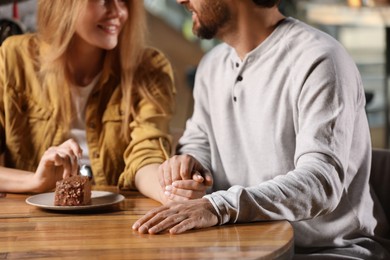 Photo of Romantic date. Couple holding hands together at table in cafe, closeup