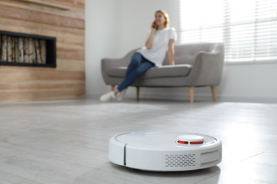 Photo of Woman resting while robotic vacuum cleaner doing her work at home
