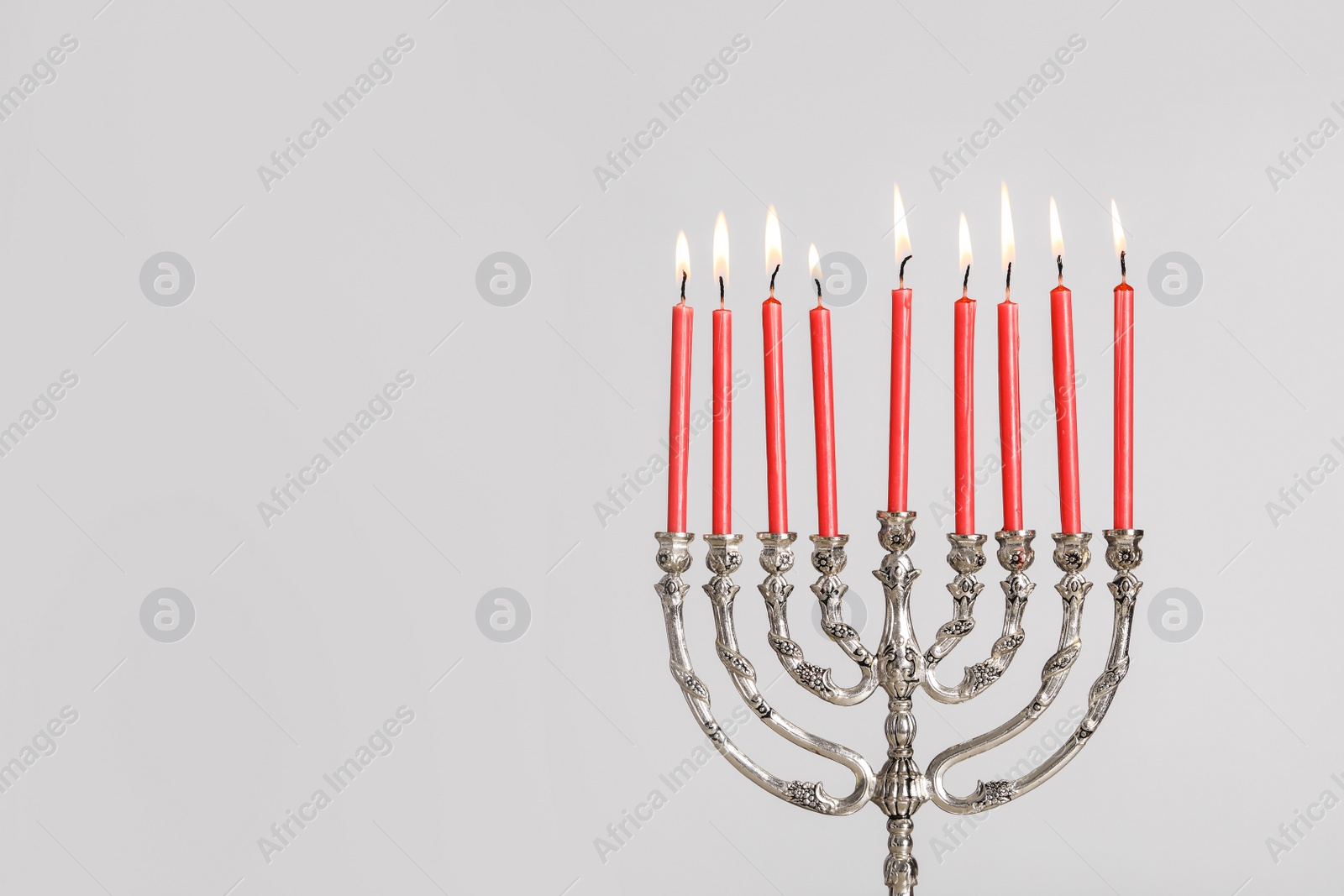 Photo of Silver menorah with burning candles on light grey background, space for text. Hanukkah celebration