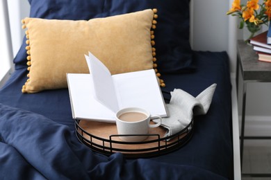 Photo of Cup of coffee and notebook on bed with fresh linens indoors