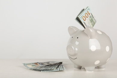 Piggy bank with dollar banknotes on table against white background. Space for text