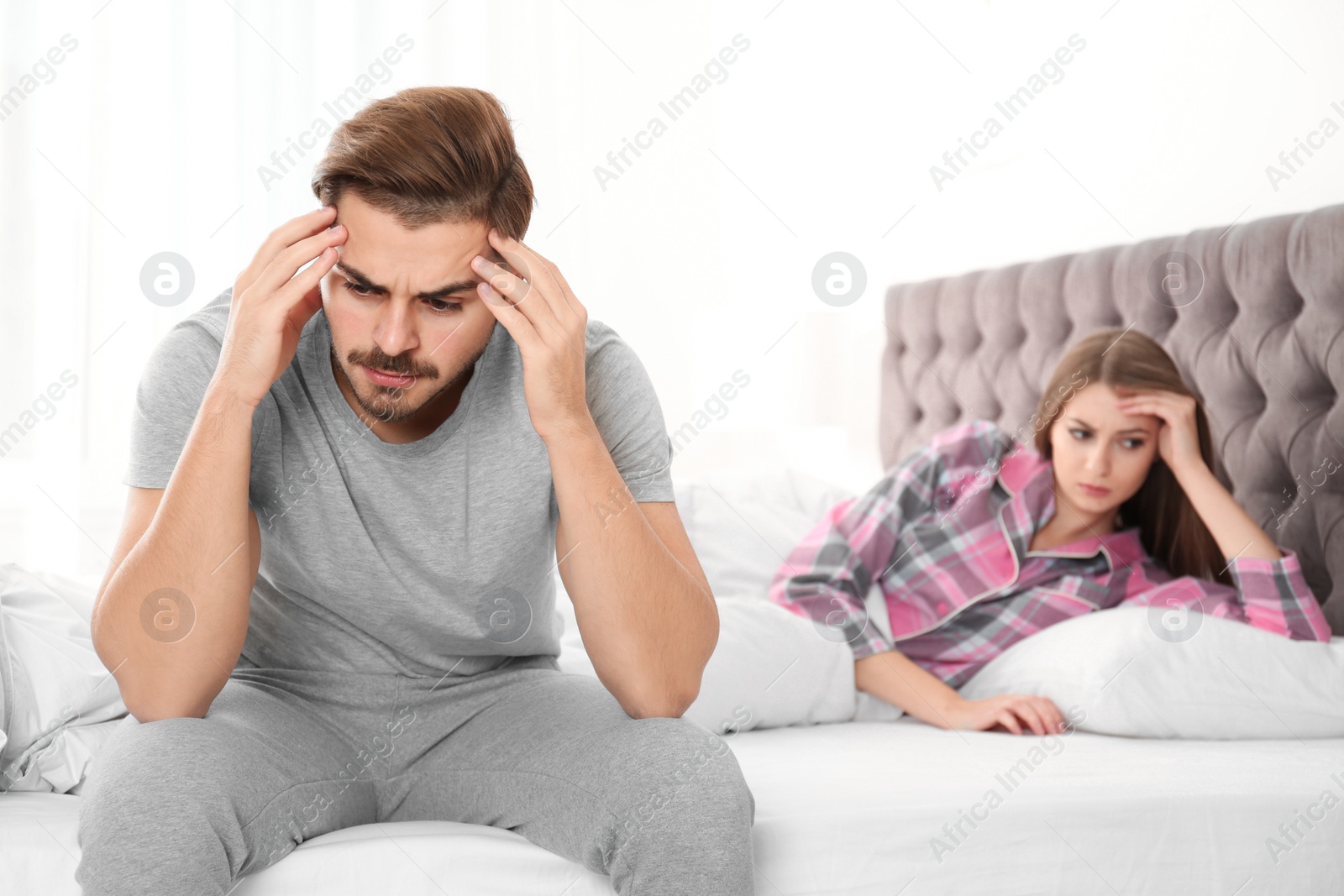 Photo of Young couple with relationship problems ignoring each other in bedroom