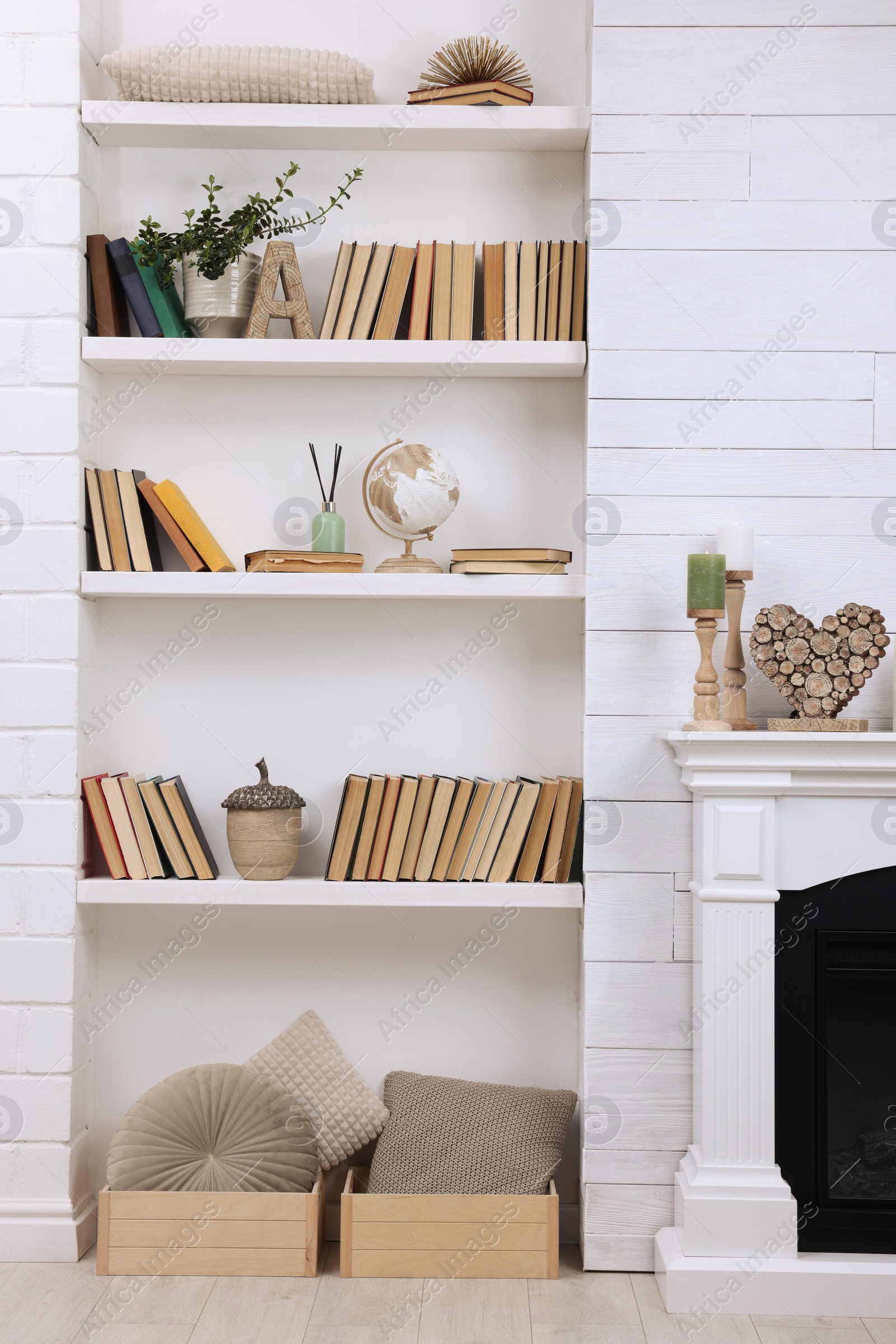 Photo of Collection of books and decor elements on shelves indoors. Interior design