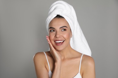 Beautiful young woman with towel on head against grey background