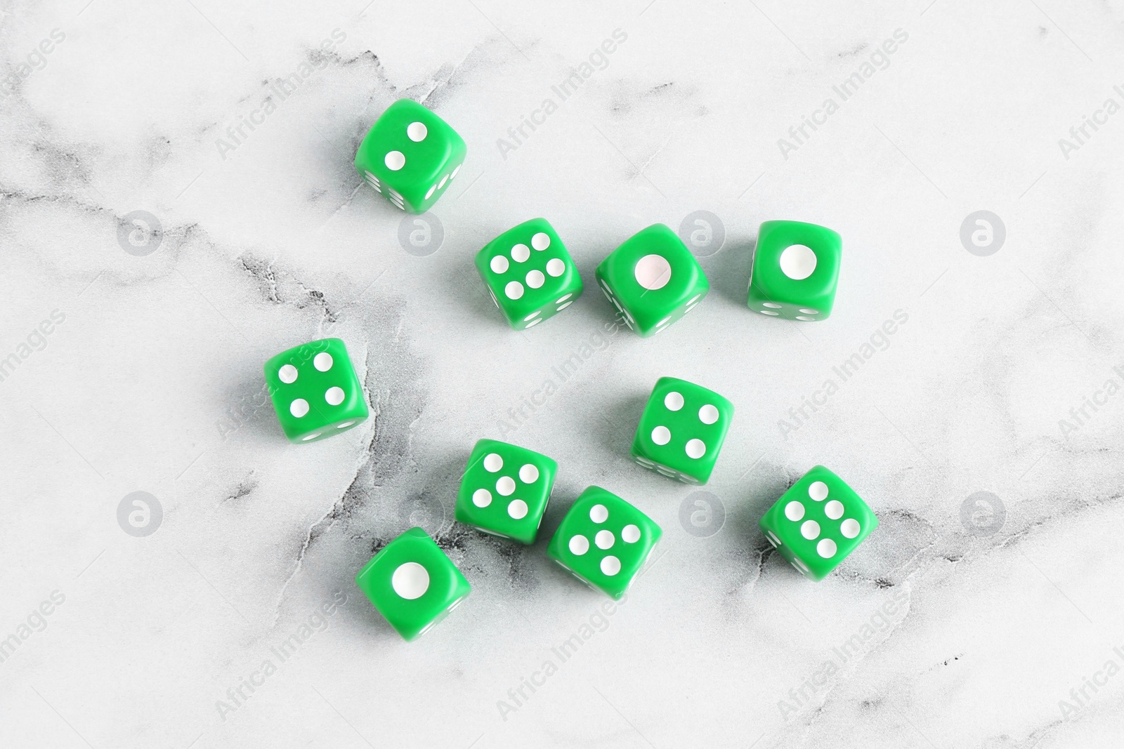 Photo of Many green game dices on white marble table, flat lay