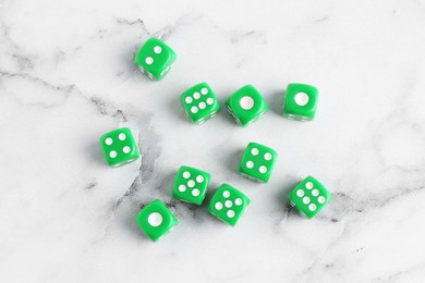 Photo of Many green game dices on white marble table, flat lay
