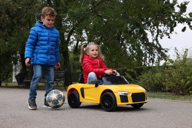 Photo of Cute little children with toy car and soccer ball having fun outdoors. Space for text
