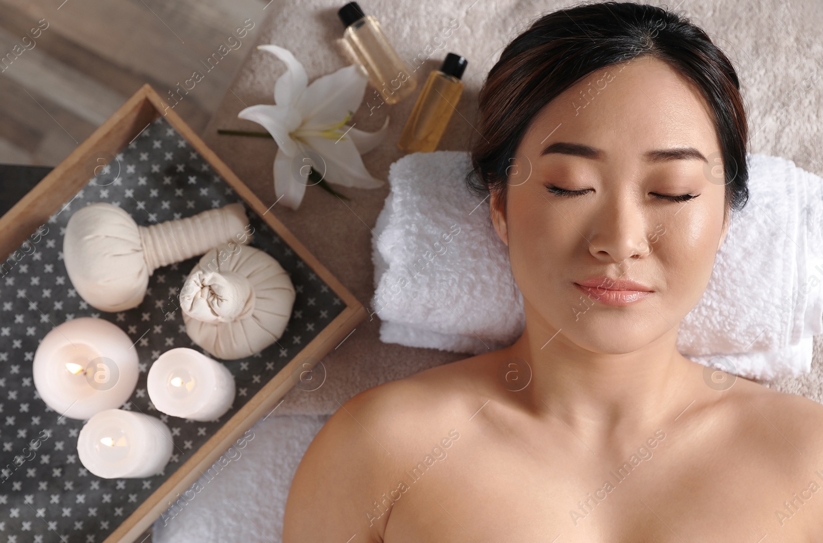 Photo of Beautiful Asian woman lying on massage table in salon, top view