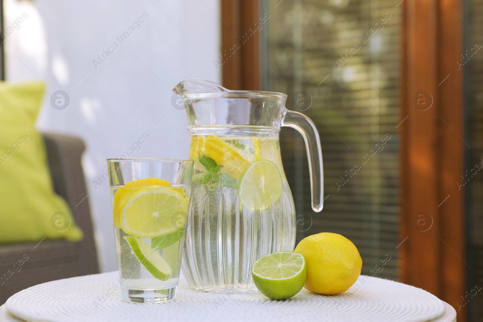 Photo of Water with lemons and limes on white table outdoors