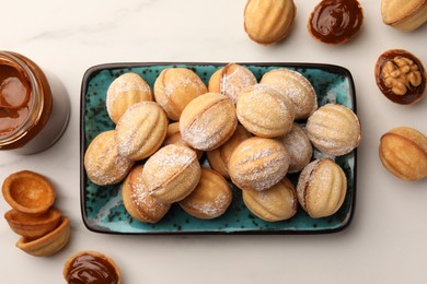 Homemade walnut shaped cookies with boiled condensed milk on white marble table, flat lay