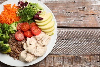 Balanced diet and healthy foods. Plate with different delicious products on wooden table, top view. Space for text