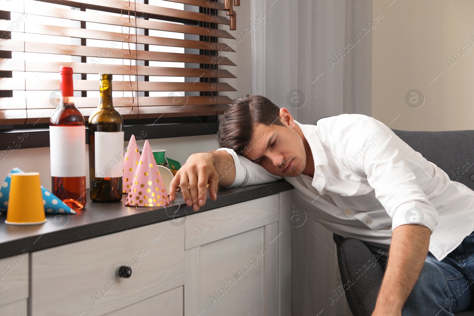 Photo of Man sleeping near window in messy room after party