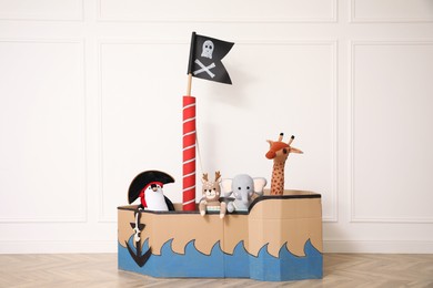 Photo of Pirate cardboard ship and toys near white wall indoors