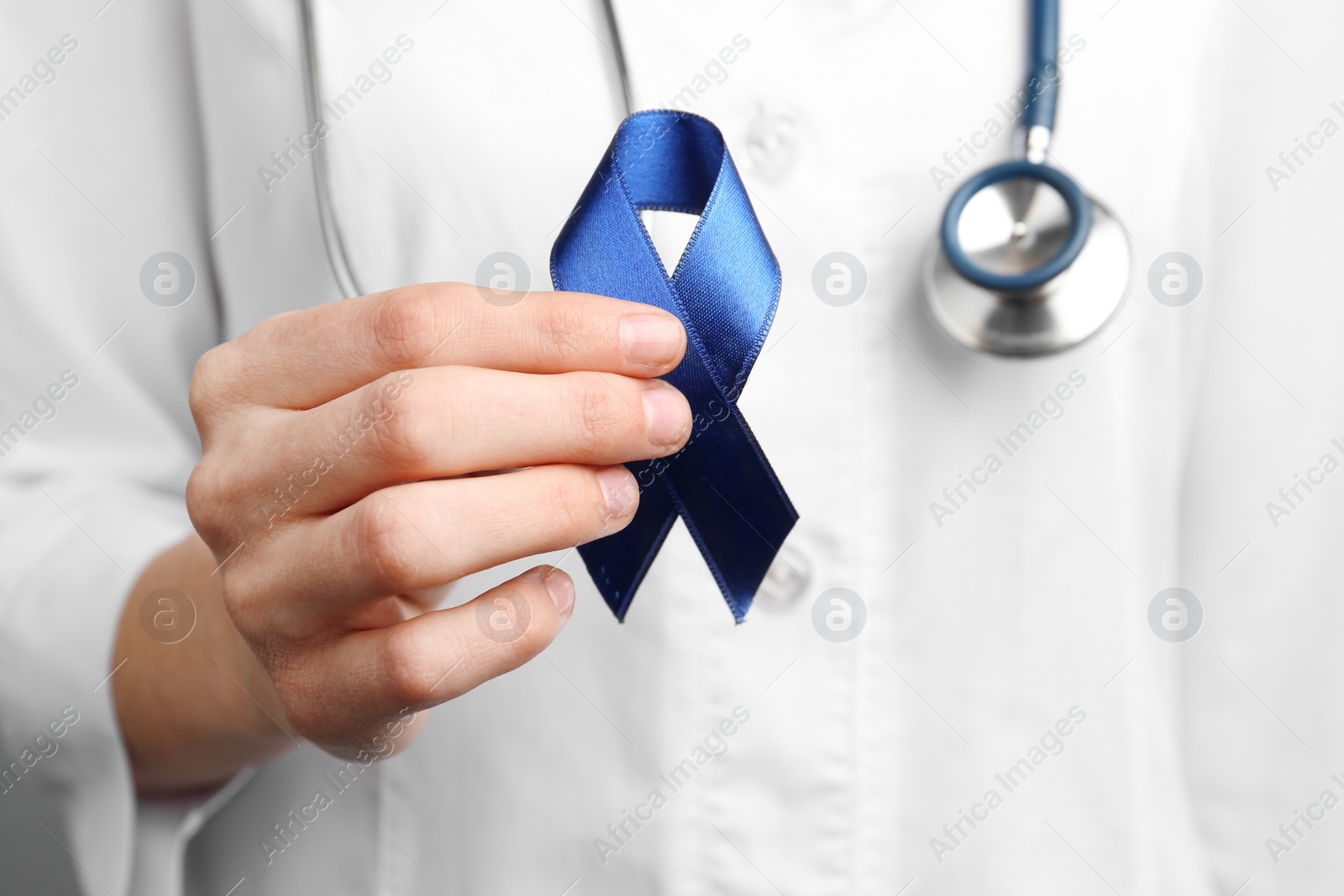 Photo of Doctor holding blue awareness ribbon, closeup view. Symbol of medical issues