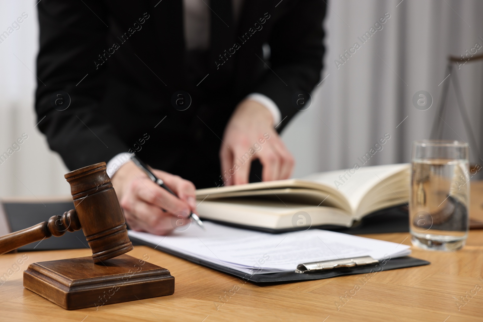 Photo of Lawyer working with documents at wooden table, focus on gavel