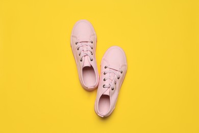 Photo of Pair of comfortable sports shoes on yellow background, flat lay