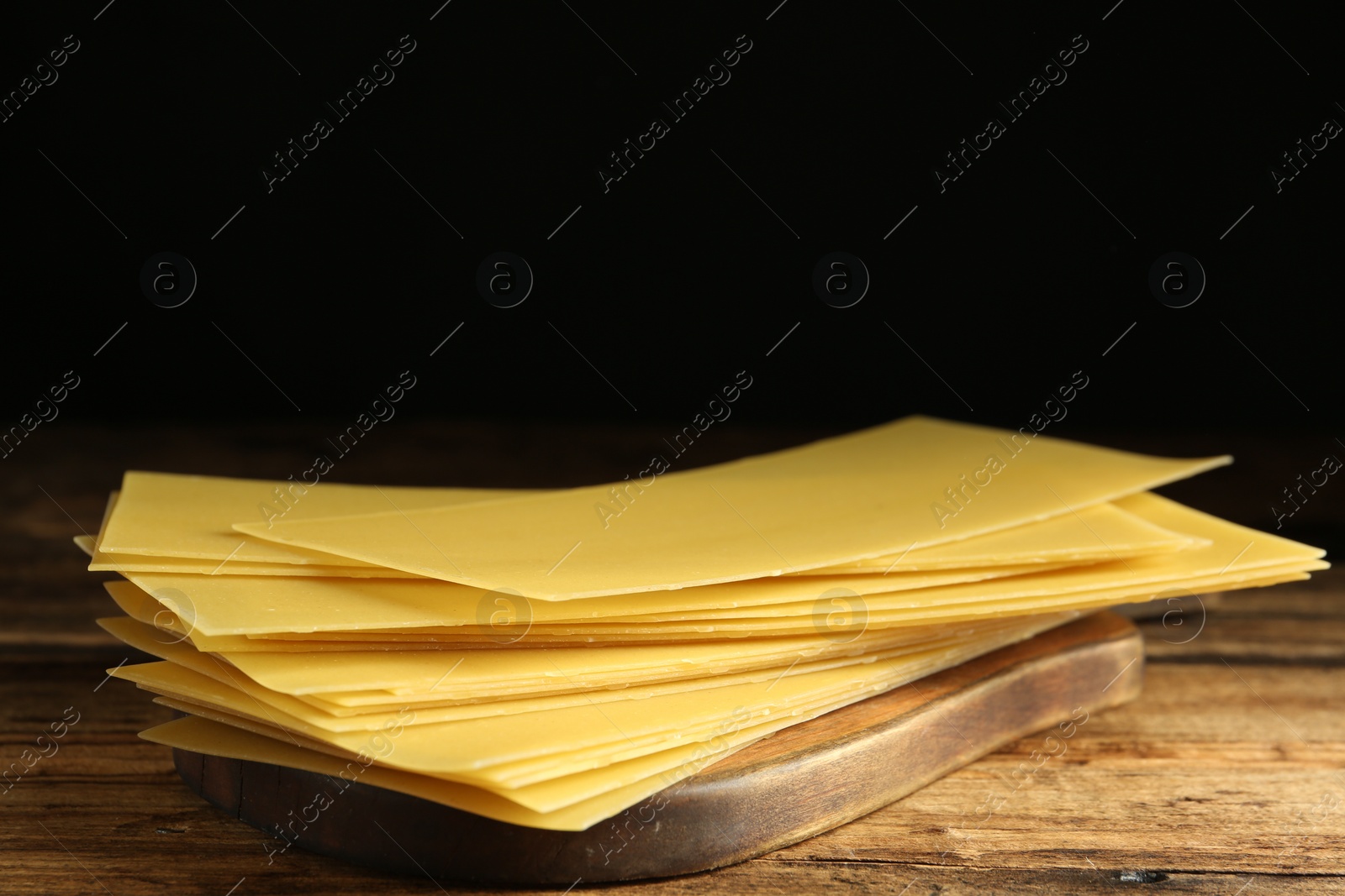 Photo of Uncooked lasagna sheets on wooden table, closeup