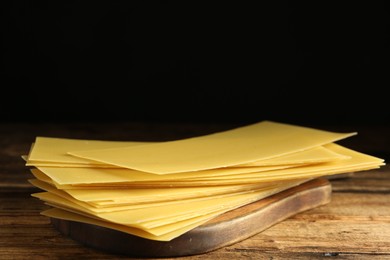 Uncooked lasagna sheets on wooden table, closeup