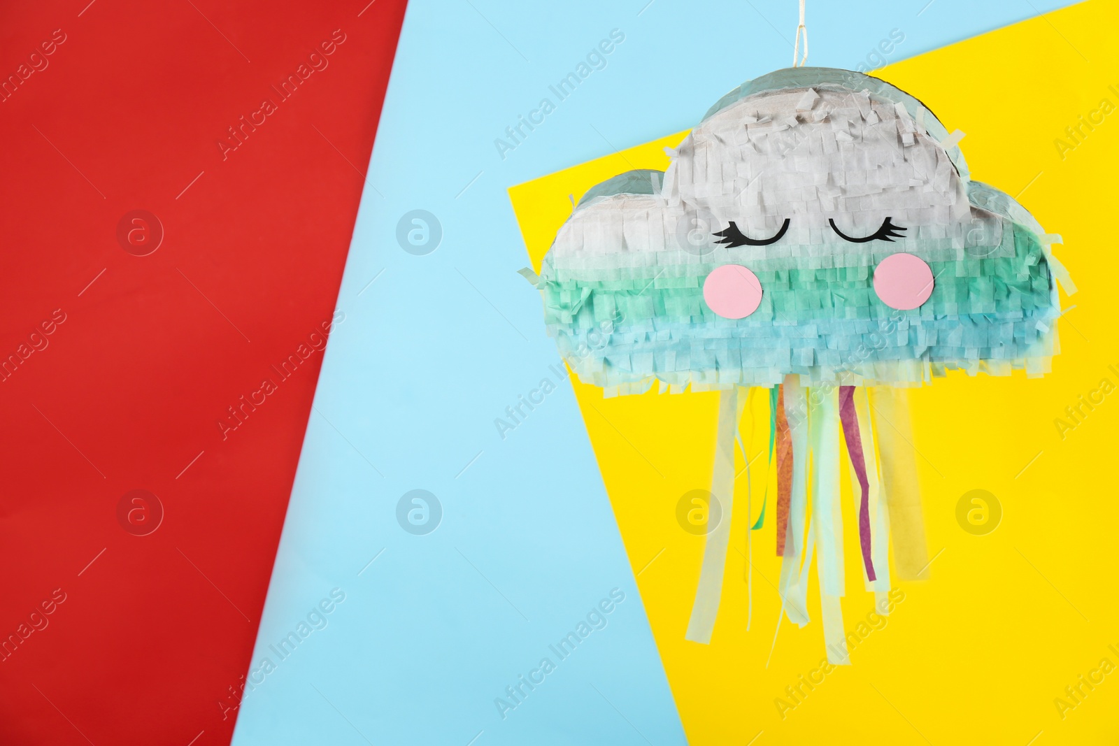 Photo of Cloud shaped pinata hanging on color background. Space for text