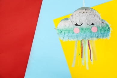 Cloud shaped pinata hanging on color background. Space for text