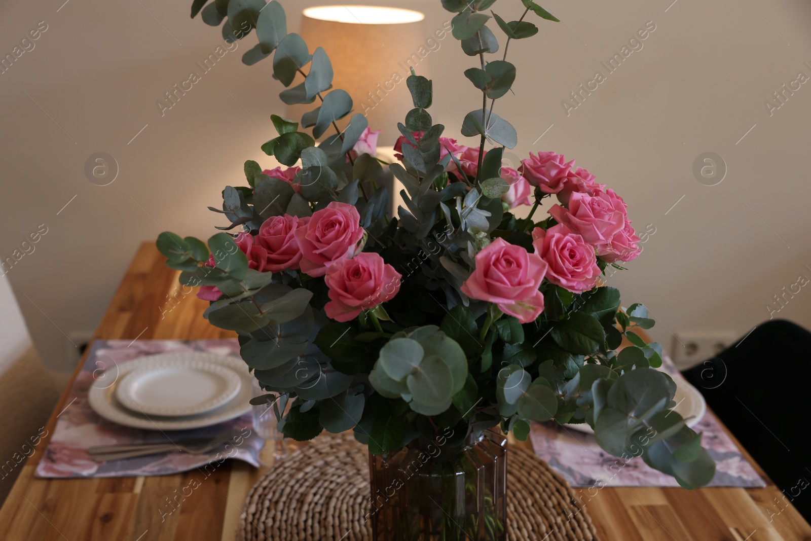 Photo of Beautiful table setting with bouquet indoors. Roses and eucalyptus branches in vase