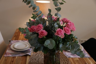 Beautiful table setting with bouquet indoors. Roses and eucalyptus branches in vase