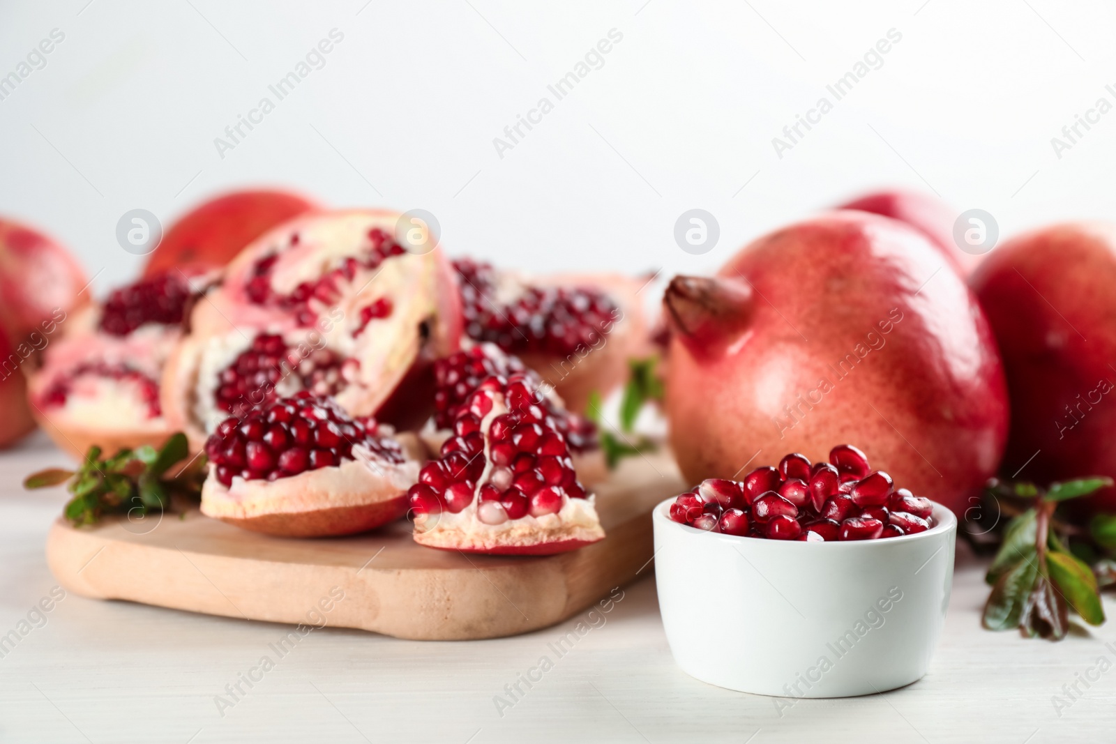 Photo of Delicious ripe pomegranates on white wooden table