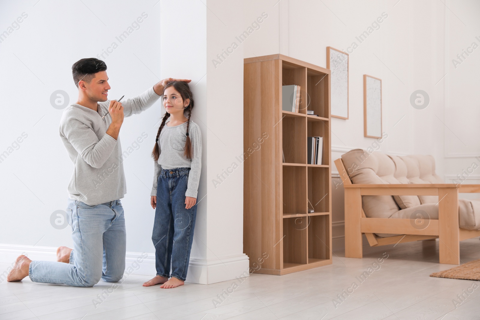 Photo of Father measuring height of his daughter near wall at home