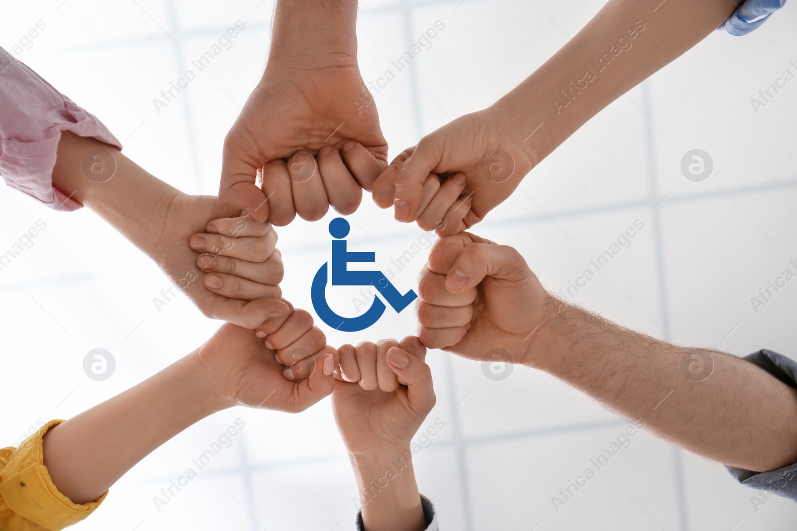 Image of Inclusion concept. People holding fists together around international symbol of access together, bottom view