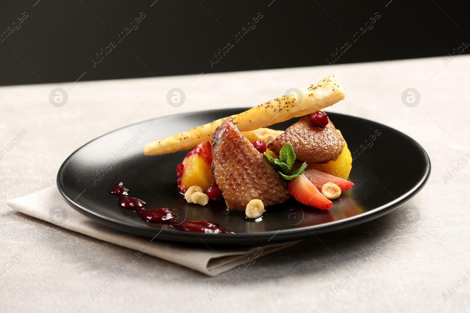 Photo of Plate with delicious chicken, parsnip and strawberries on grey table. Food stylist