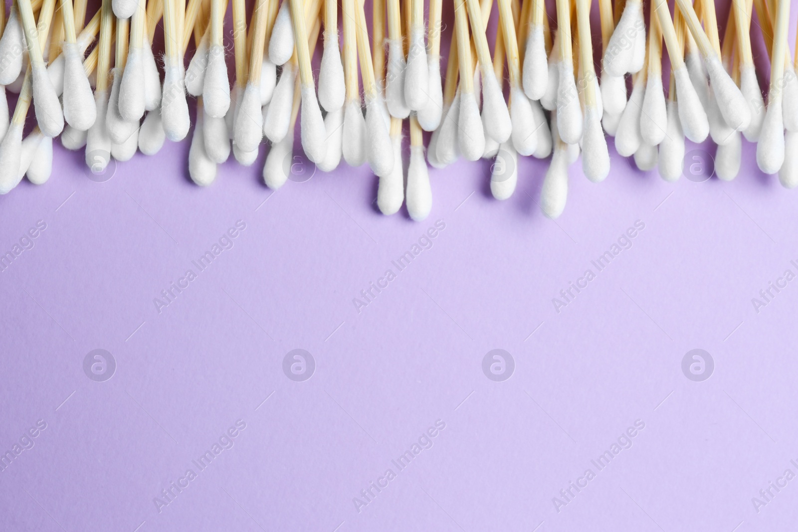 Photo of Many cotton buds on violet background, flat lay. Space for text