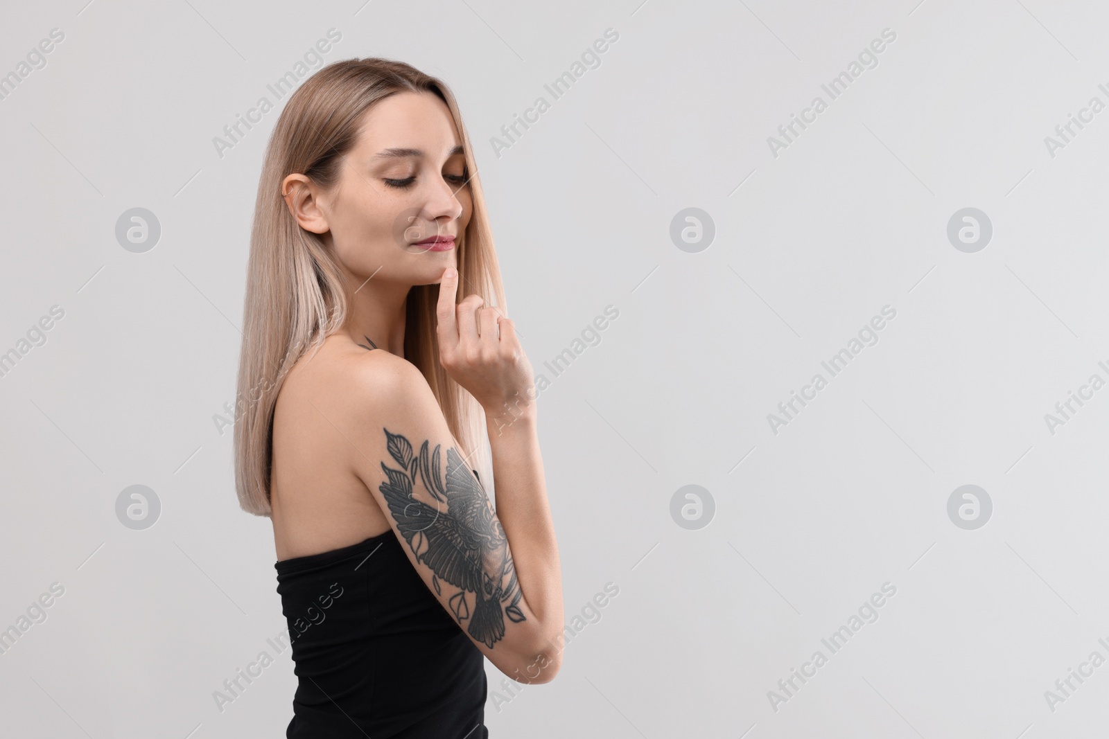 Photo of Portrait of beautiful tattooed woman on light background, space for text